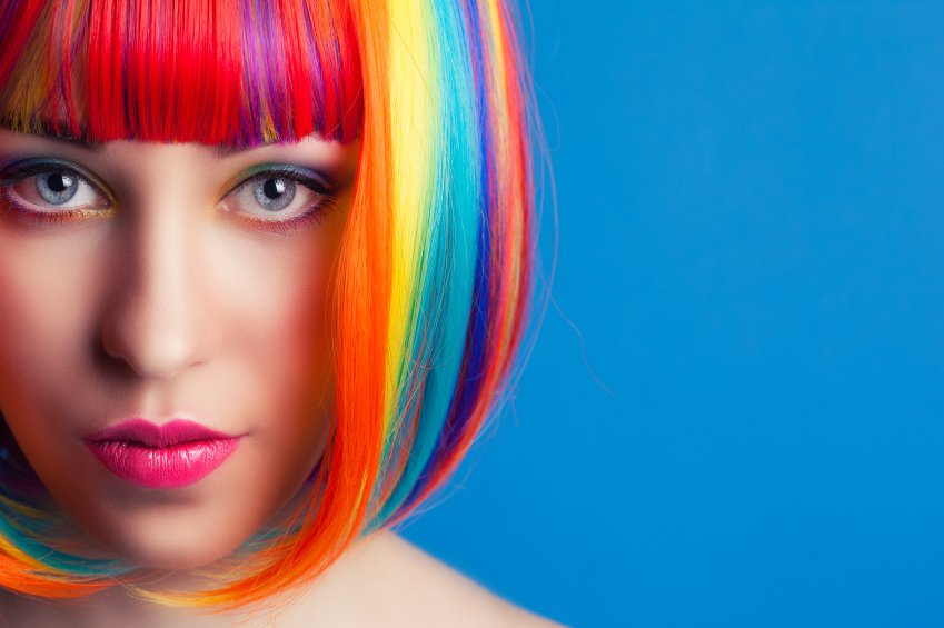 beautiful woman wearing colorful wig against blue background